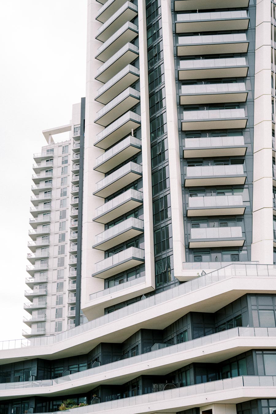 Modern high-rise residential building with glass balconies and windows, showcasing urban architecture design.