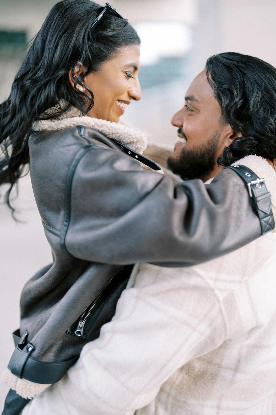 A couple happily embracing each other, wearing cozy winter jackets.
