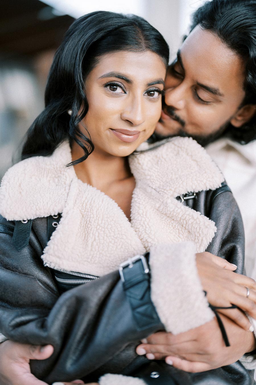 A couple embracing lovingly, with the woman in a cozy shearling jacket.