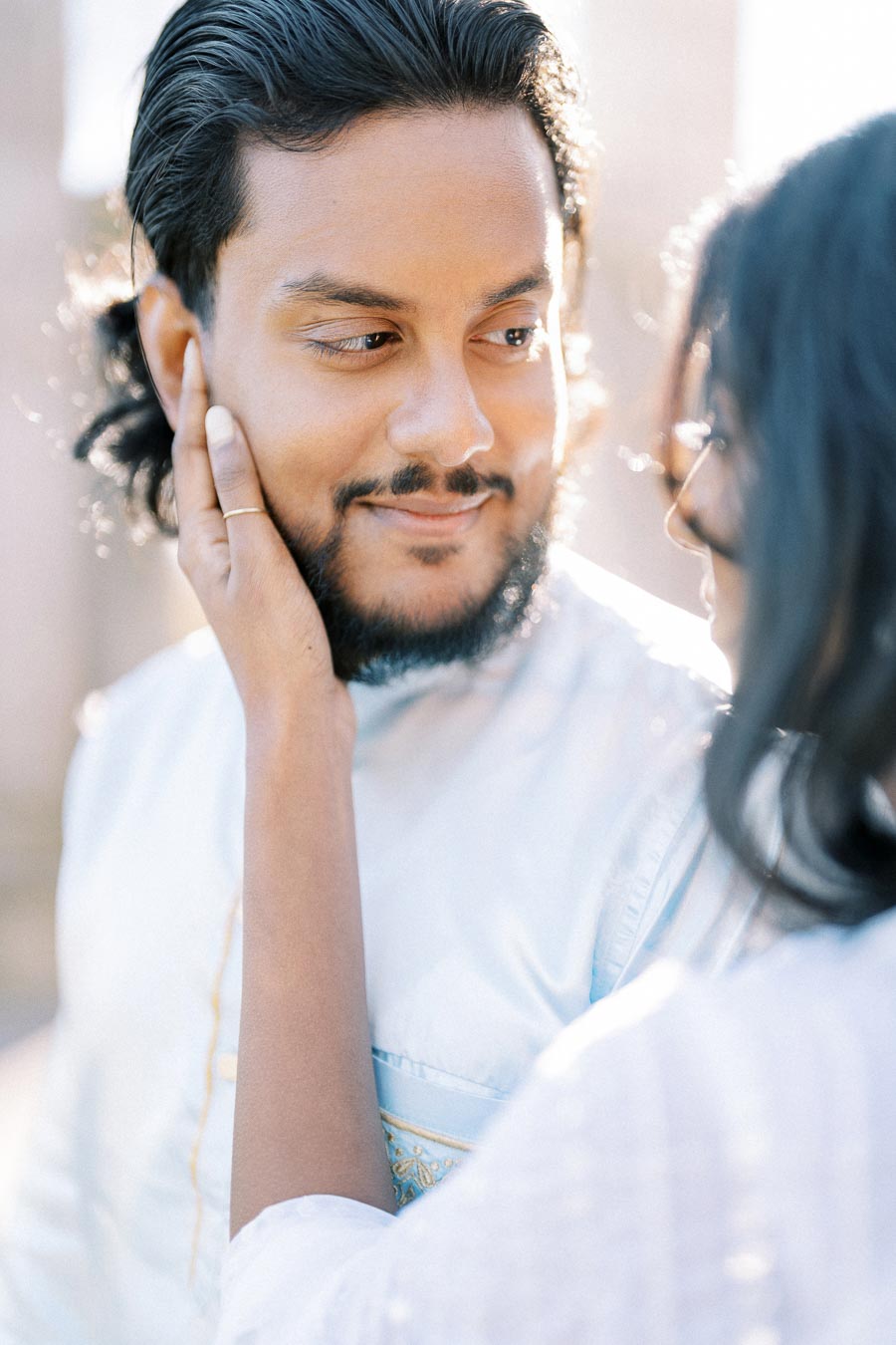 A couple sharing a tender moment, woman gently touching the man's face with affection, both smiling and enjoying a serene, intimate connection.