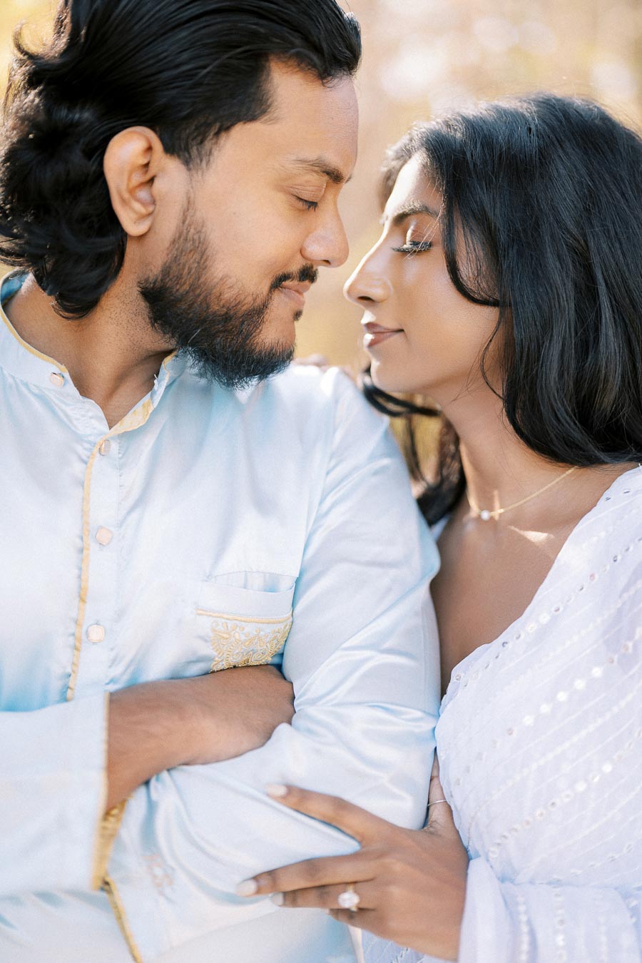 Young couple in traditional attire embracing outdoors, showcasing love and cultural elegance.