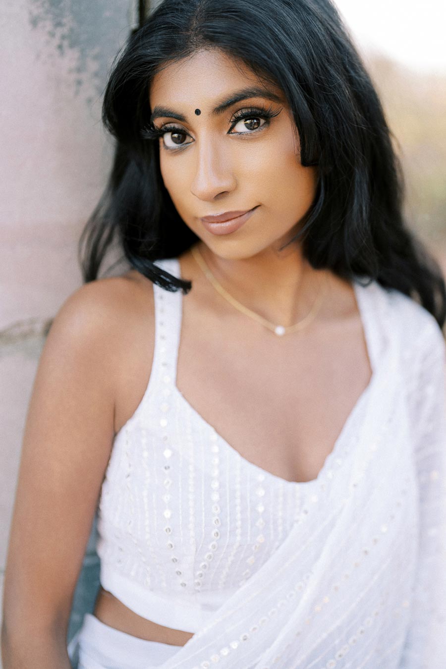 Portrait of a woman in a white saree, showcasing elegant traditional attire with intricate embroidery, set against a softly blurred background.