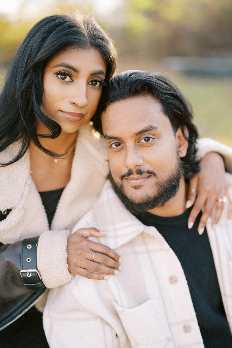 Young couple embracing in a park, wearing cozy winter jackets; couple portrait photography.