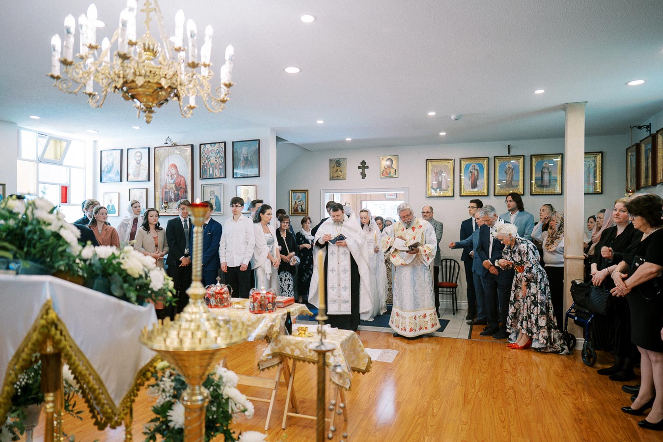 Orthodox Church ceremony with priests leading a service, congregation gathered, and religious icons adorning the walls.