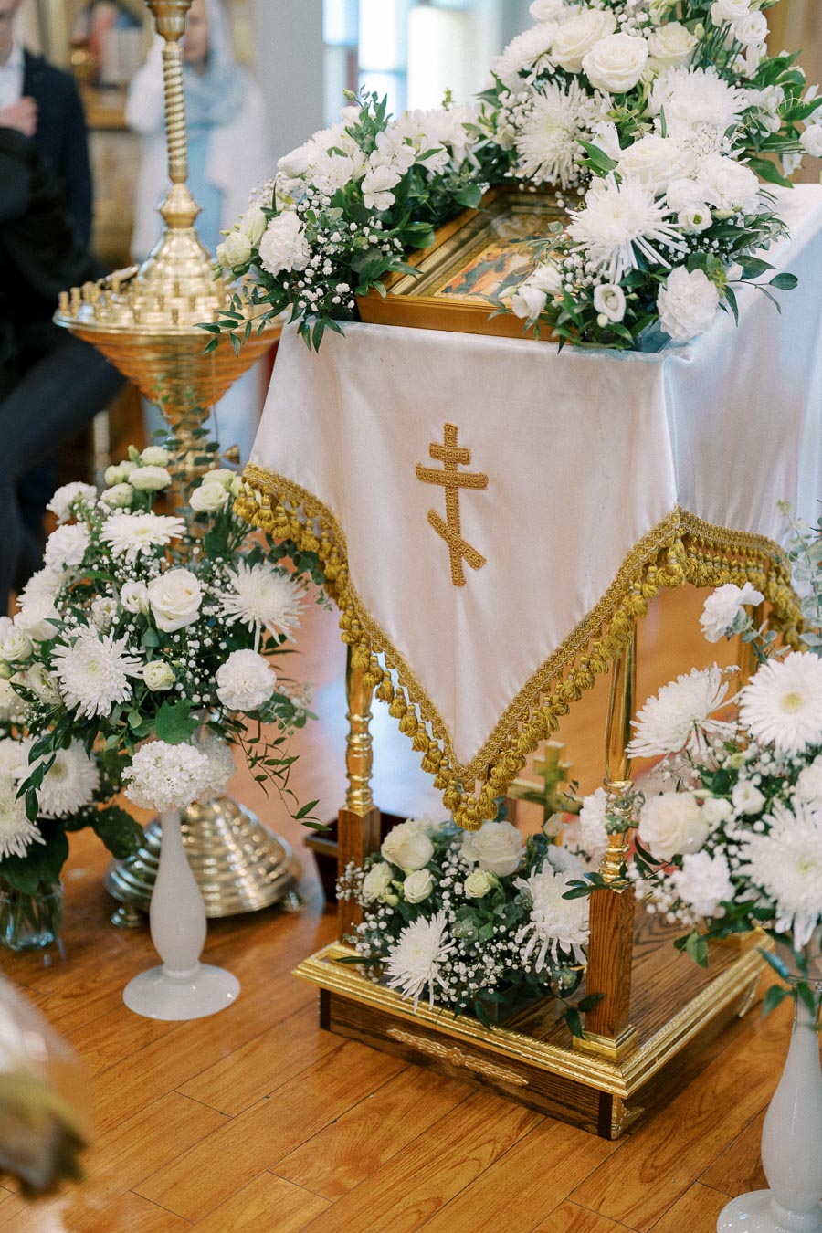 Orthodox church altar decorated with white flowers and ornate gold accents.