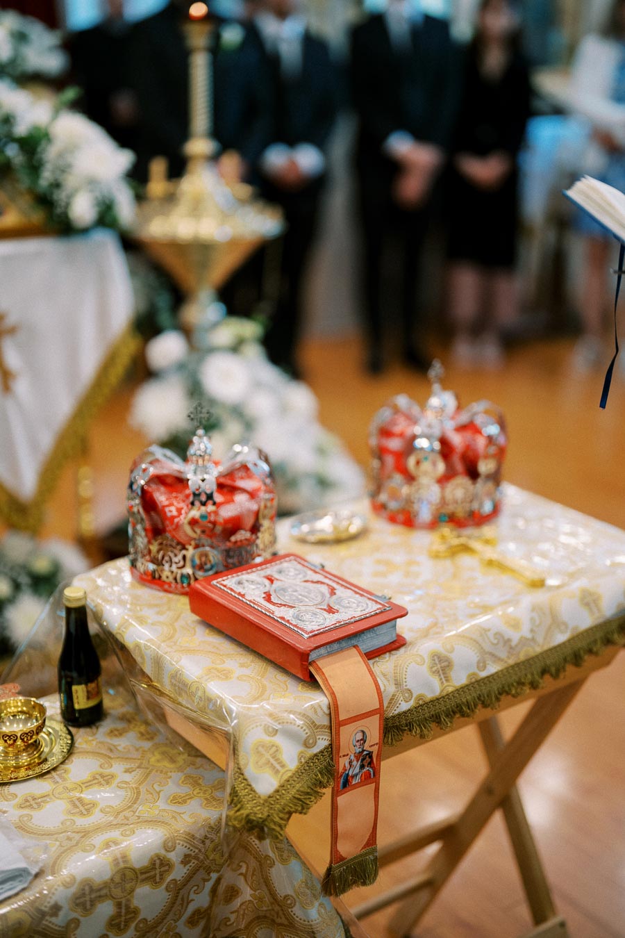 Orthodox wedding ceremony with crowns, a prayer book, and religious symbols on a decorated altar table.