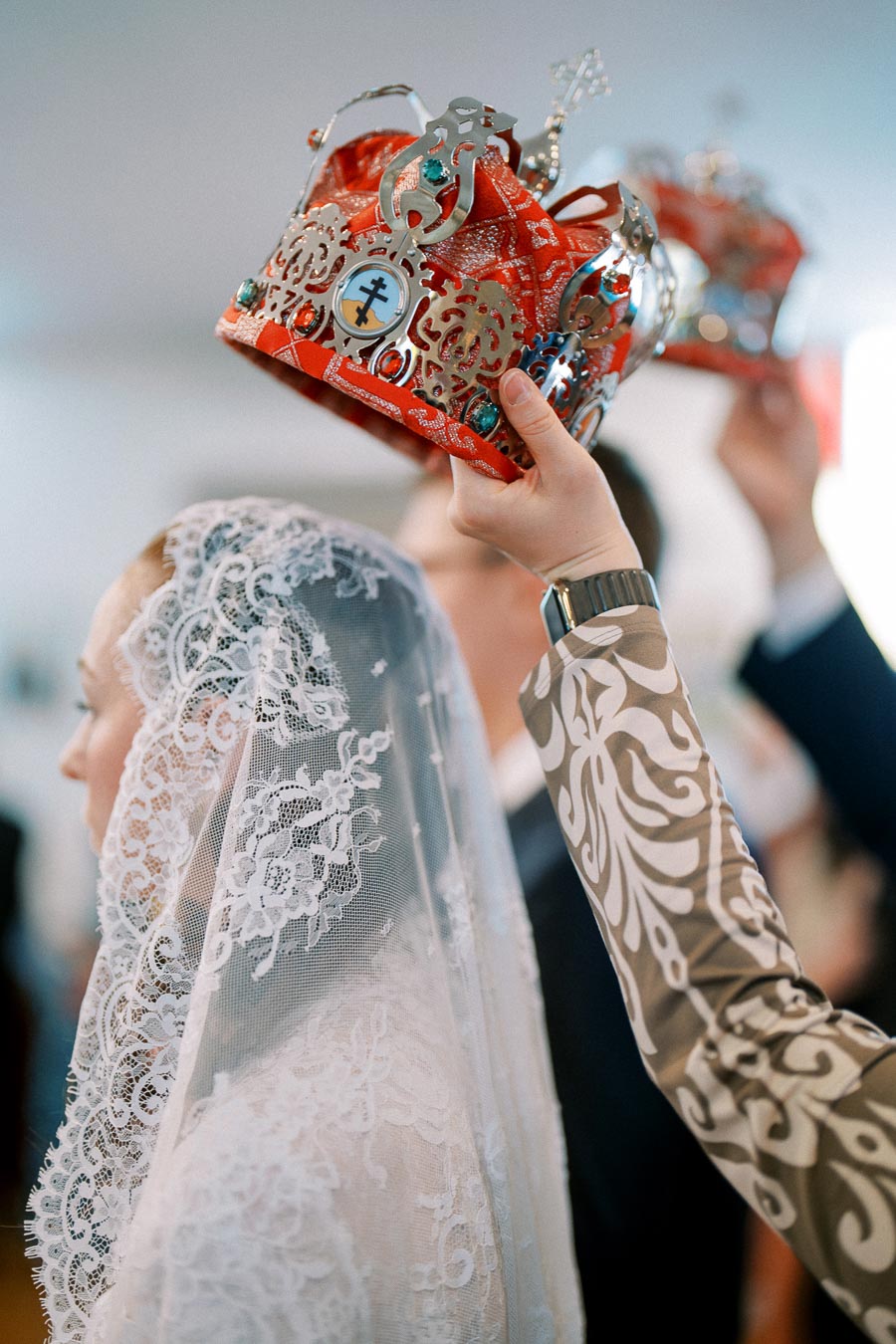 Orthodox wedding ceremony with bride wearing a lace veil and ornate crown, symbolizing union and tradition.