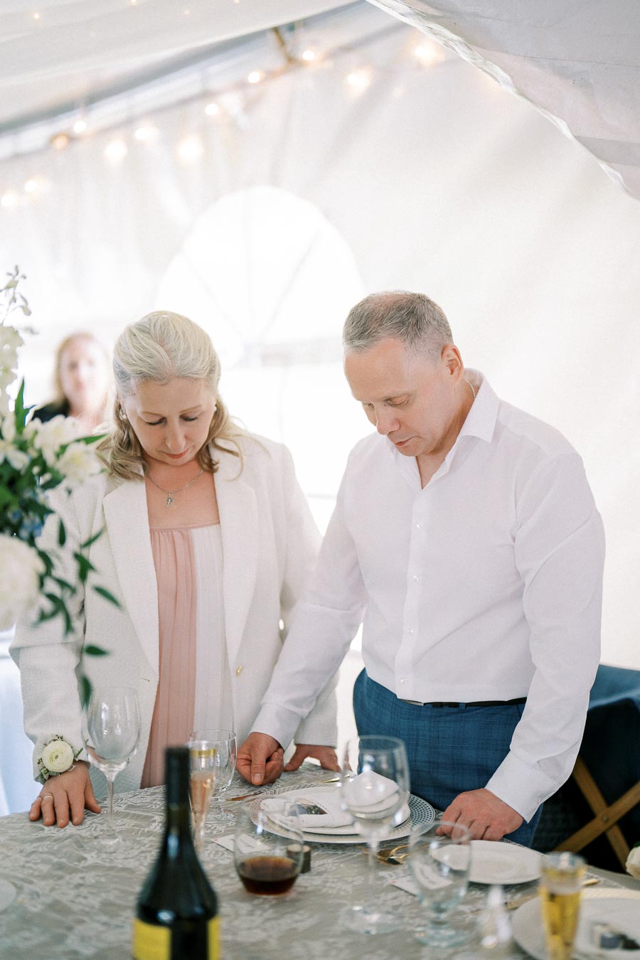 Two individuals standing together at a formal dining table, with elegant table settings and ambient lighting.