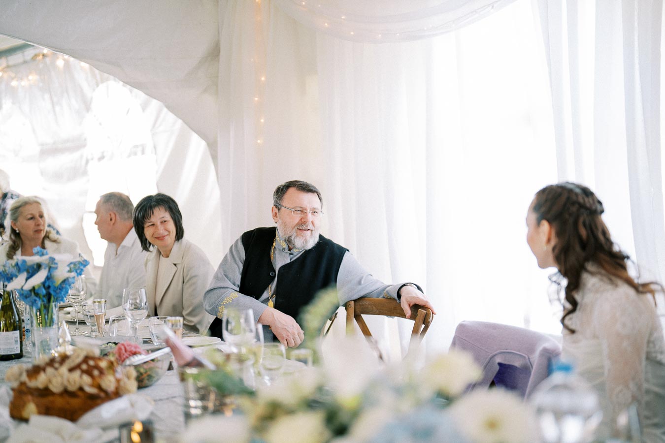 A group of people sitting at a beautifully arranged table during a formal gathering, with elegant decorations and soft lighting creating a warm atmosphere.