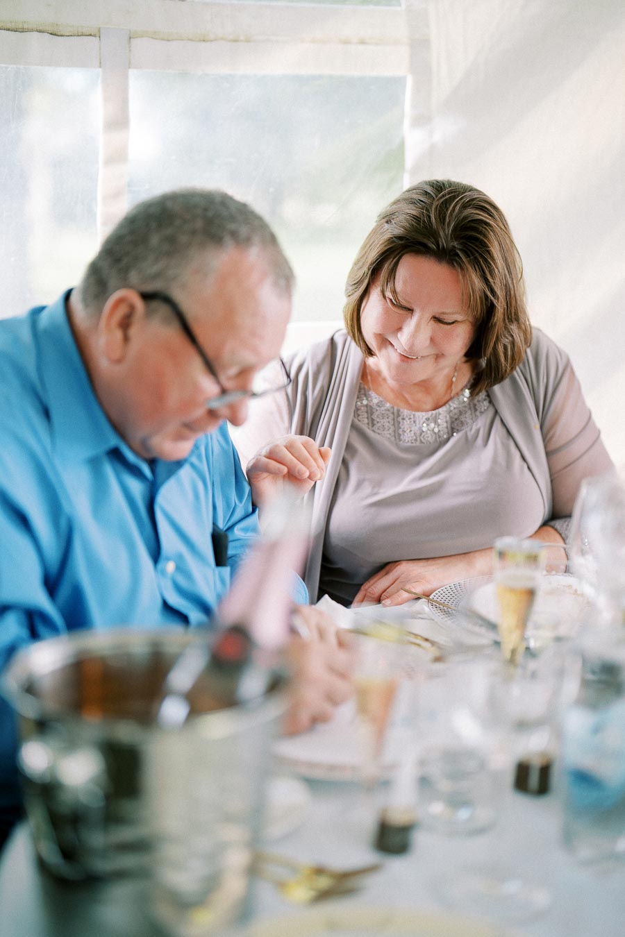 Elderly couple enjoying a meal together at an elegant dining table with champagne and tableware, conveying warmth and companionship.