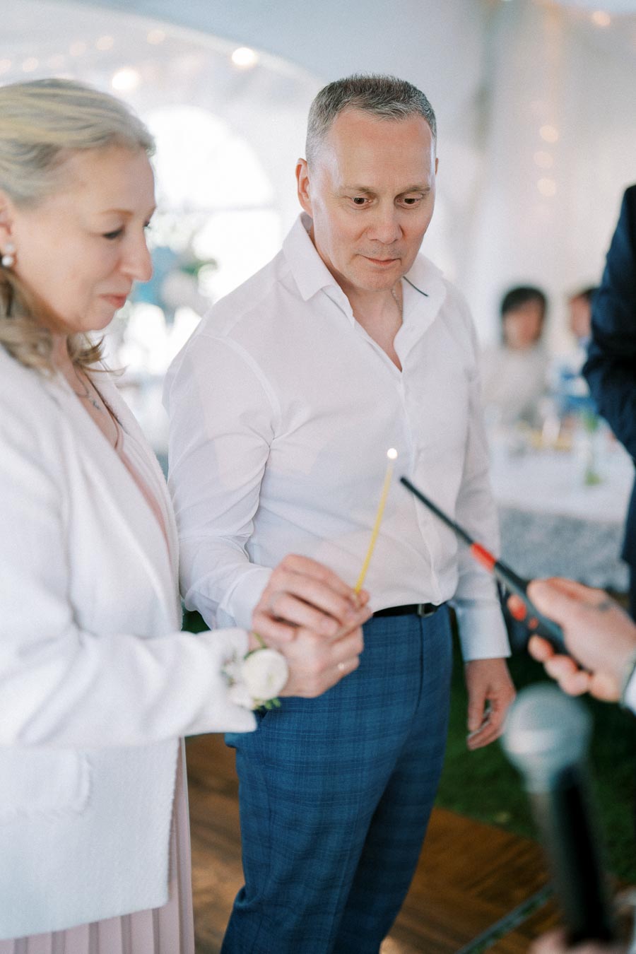A couple lighting a candle together during a wedding ceremony, symbolizing unity and new beginnings.