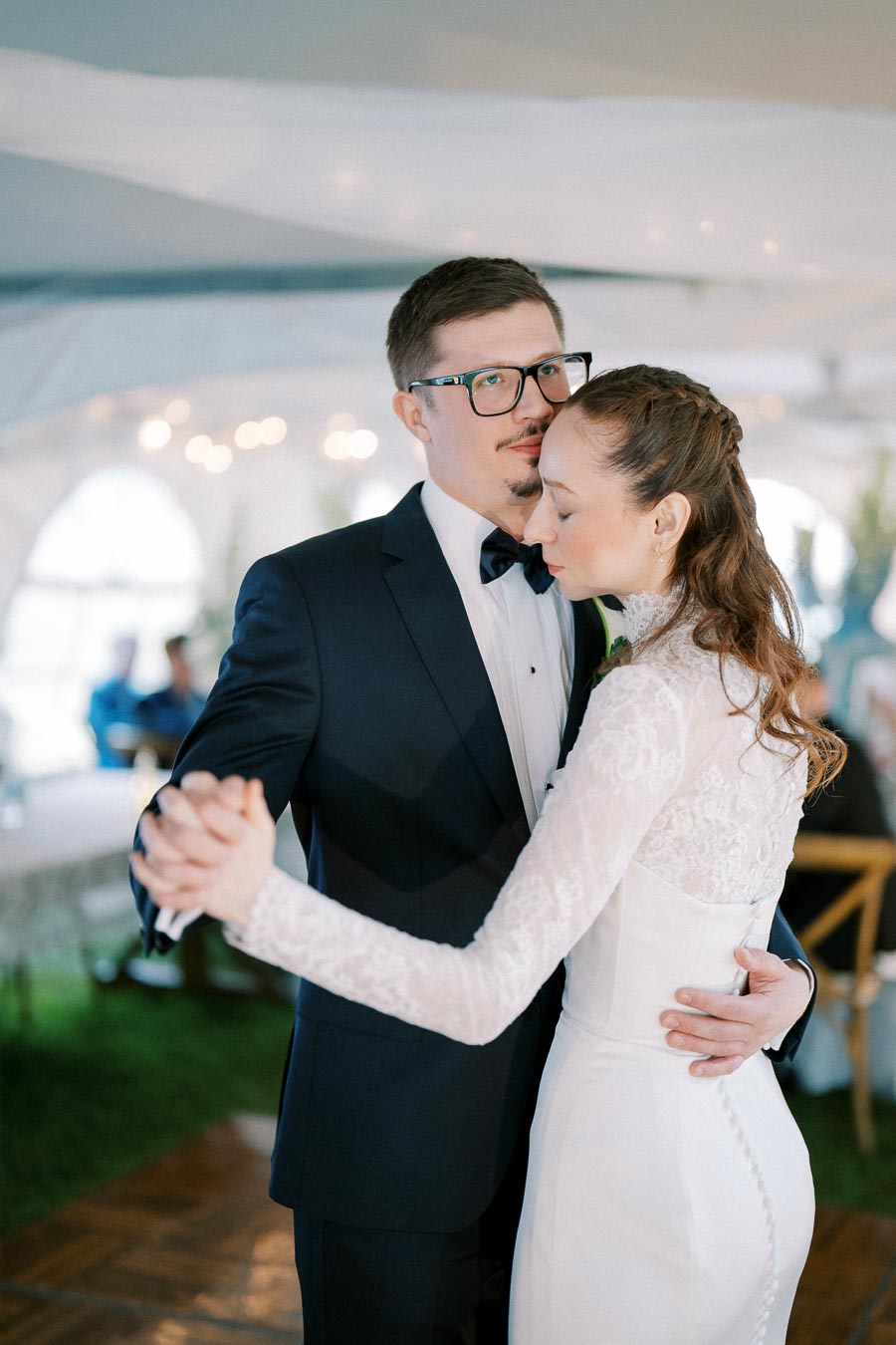 Elegant couple sharing a romantic first dance at a wedding reception, with the groom in a classic black tuxedo and the bride in a stunning lace wedding gown.