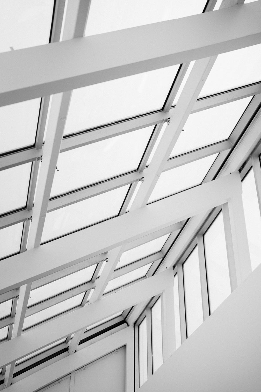 Modern glass ceiling with structural beams in a minimalist architectural design, emphasizing natural light and open space.