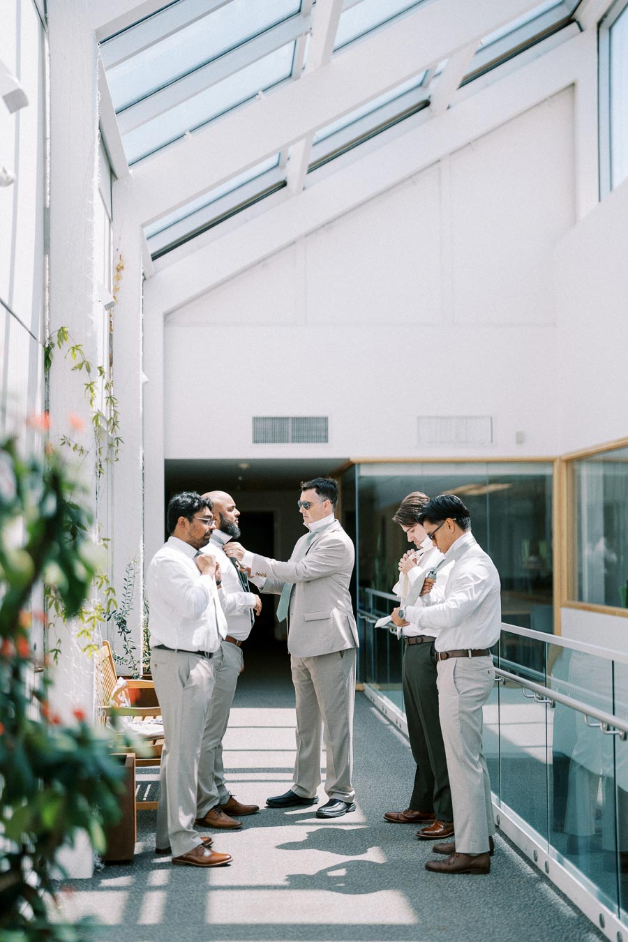 A group of well-dressed men in an elegant hallway, adjusting ties and suits, preparing for a formal event.