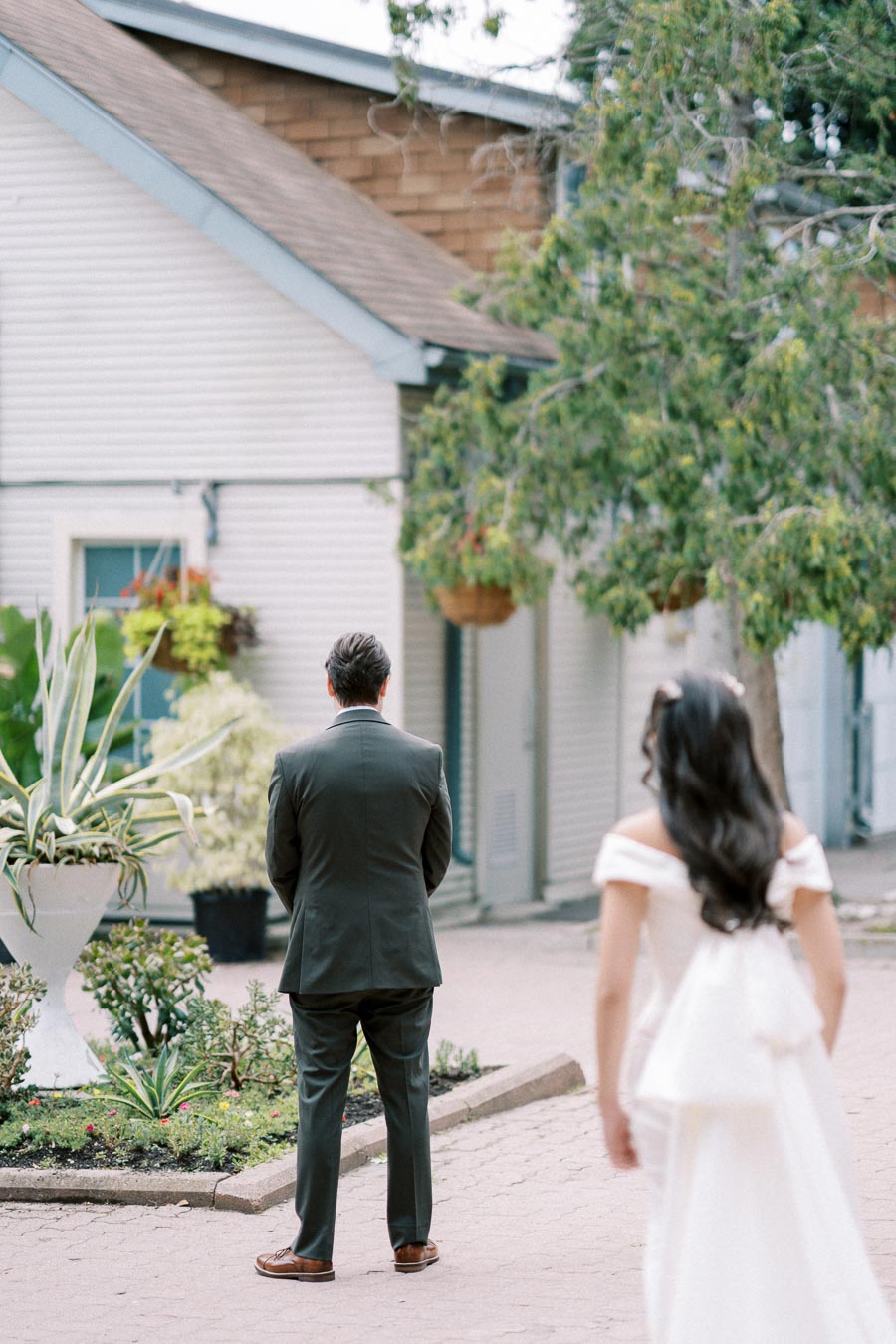 Bride approaching groom for first look in garden courtyard on wedding day.