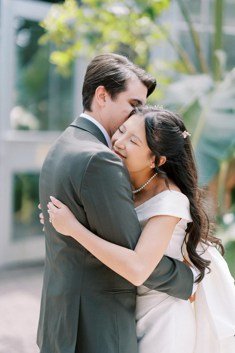 A bride and groom embracing lovingly in a garden setting on their wedding day.