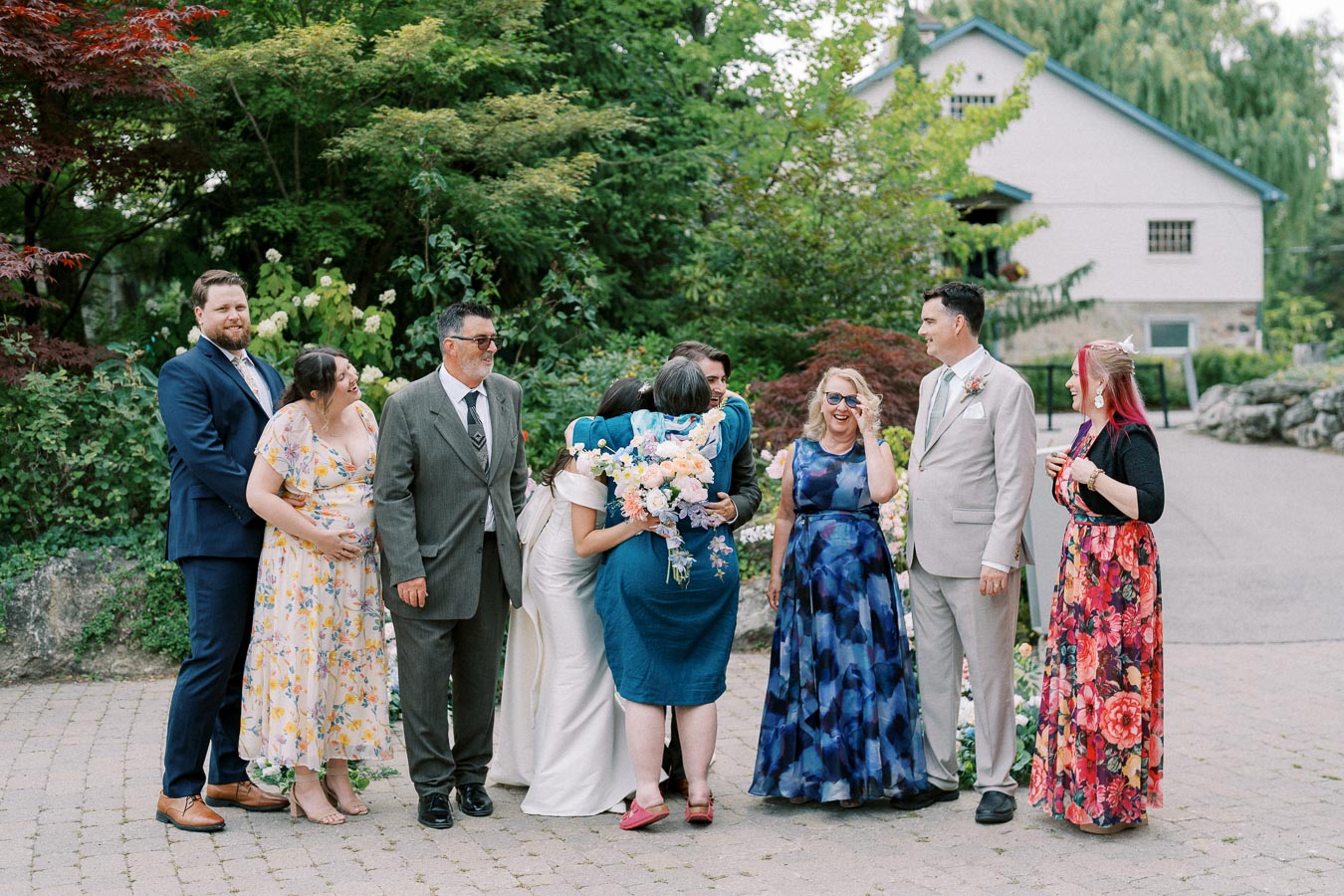 A joyful wedding group photo featuring elegantly dressed guests against a lush garden backdrop, capturing a moment of celebration and happiness.