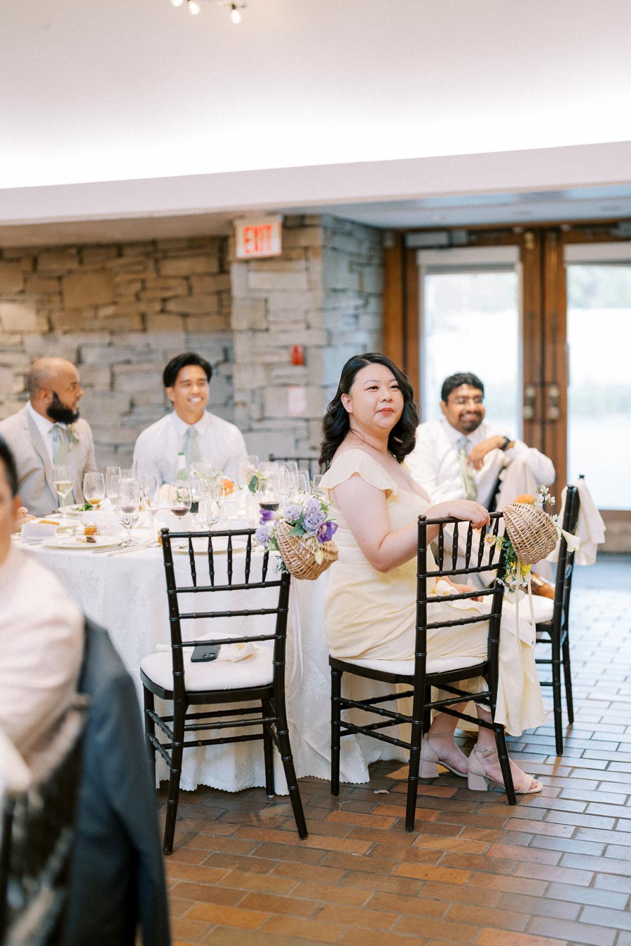 Wedding reception scene with guests seated at a beautifully adorned table, enjoying the celebration in a warmly lit venue.