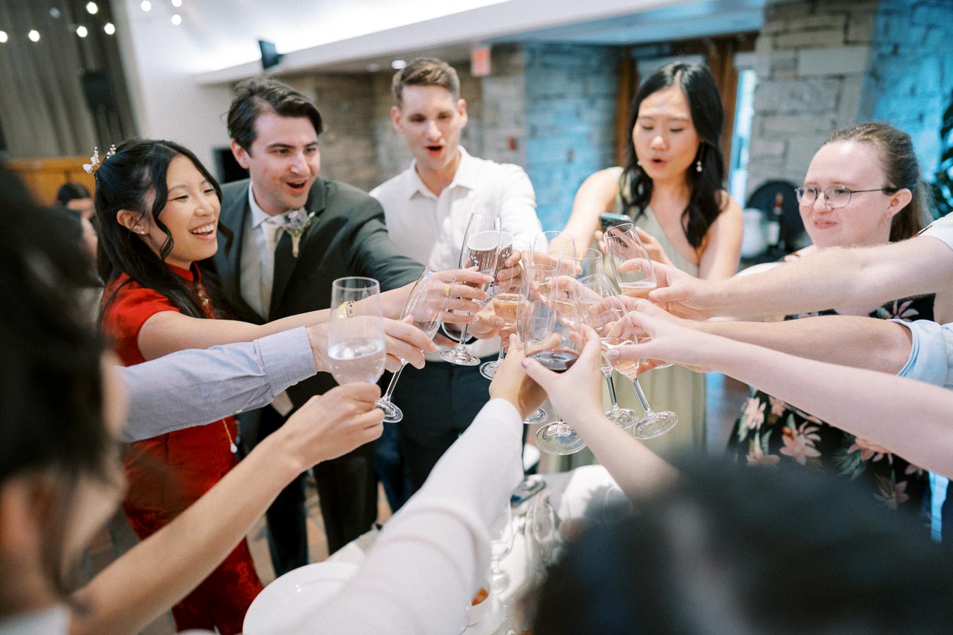 A group of people raising their glasses for a toast at a wedding celebration, capturing a joyful and festive atmosphere.