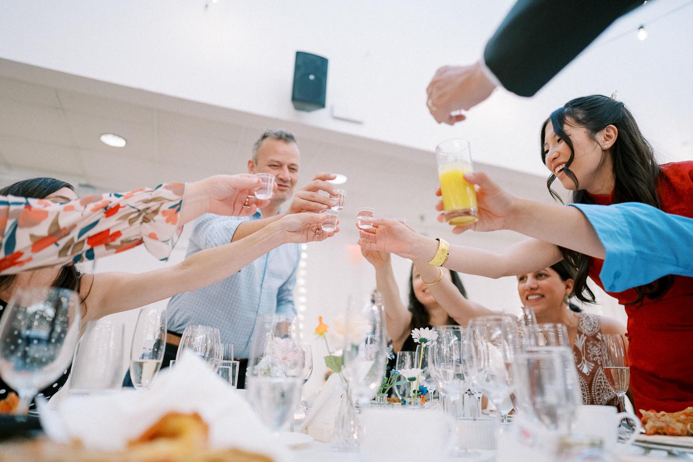 Group of happy people toasting with drinks at a festive table setting indoors.