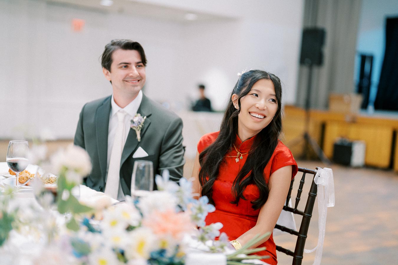A joyful couple at a wedding reception, dressed elegantly and smiling.