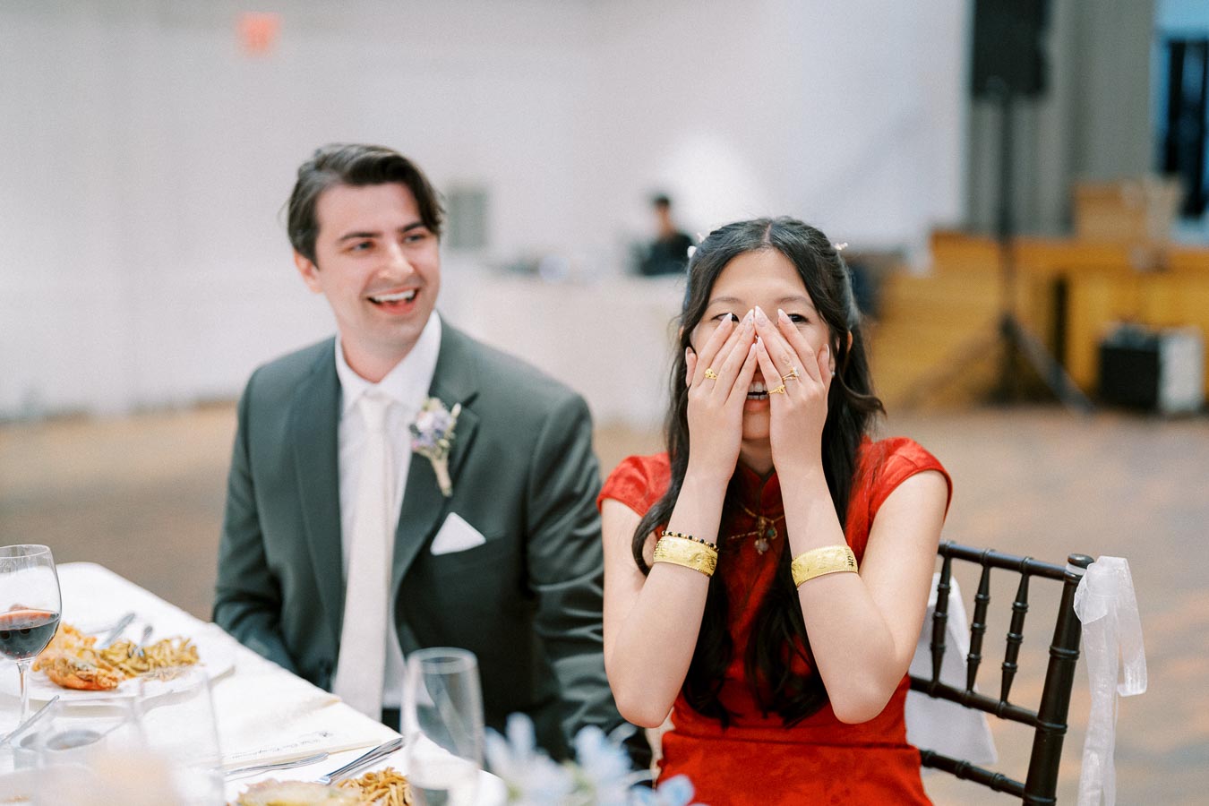 A joyful moment captured at a wedding reception, with the couple sharing a laugh and a surprise.