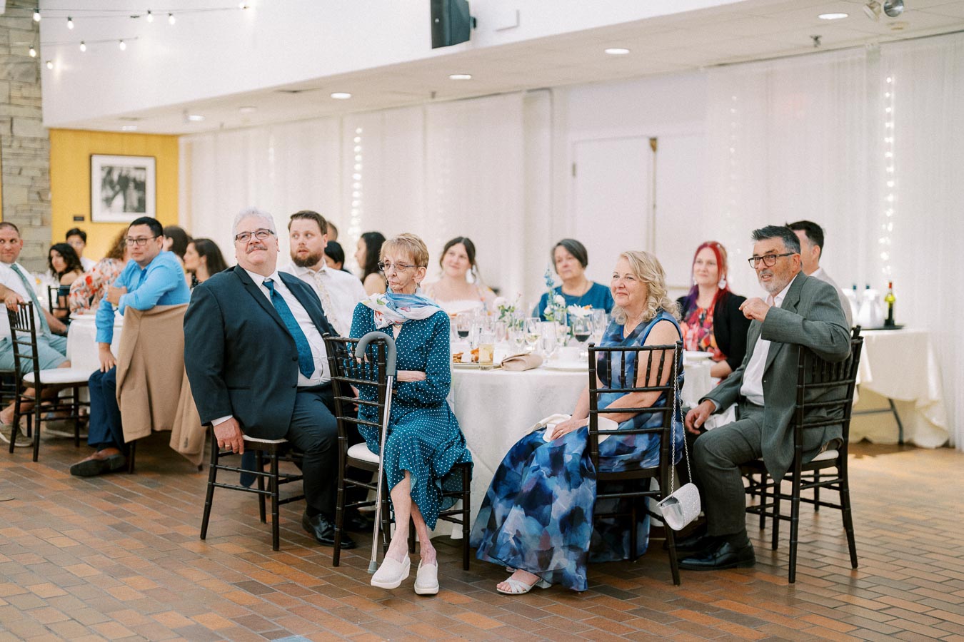 Guests at a formal event seated at tables, attentively watching a presentation or performance.