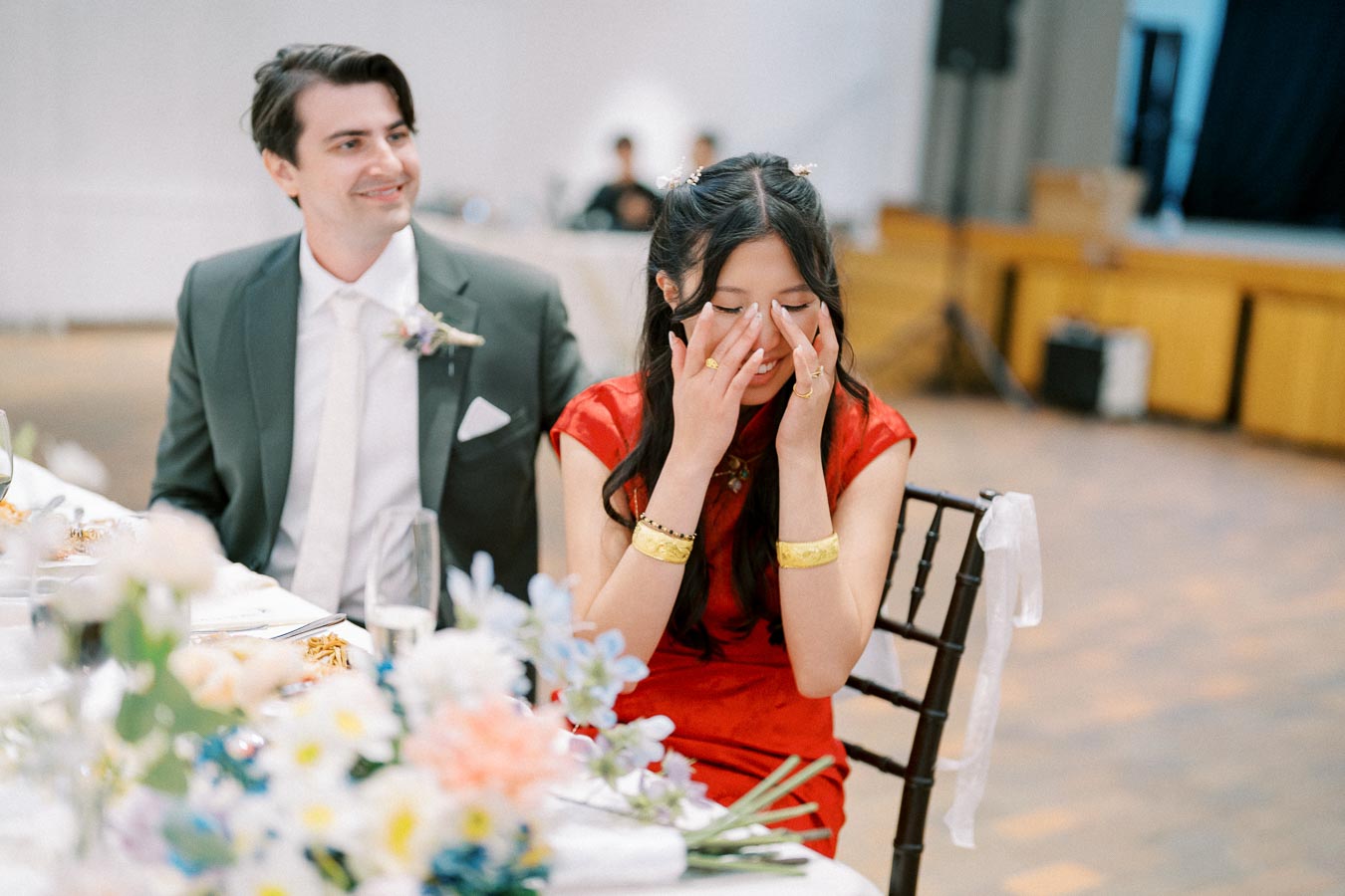 A joyful moment at a wedding reception with a couple seated at a decorated table.