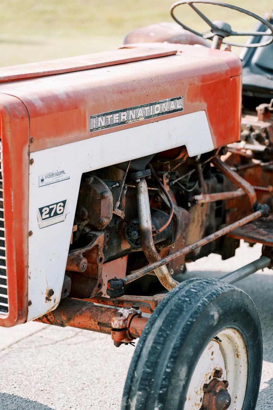 Close-up of a vintage International 276 tractor, showcasing its worn machinery and red and white exterior. Ideal for farming enthusiasts and machinery history buffs.