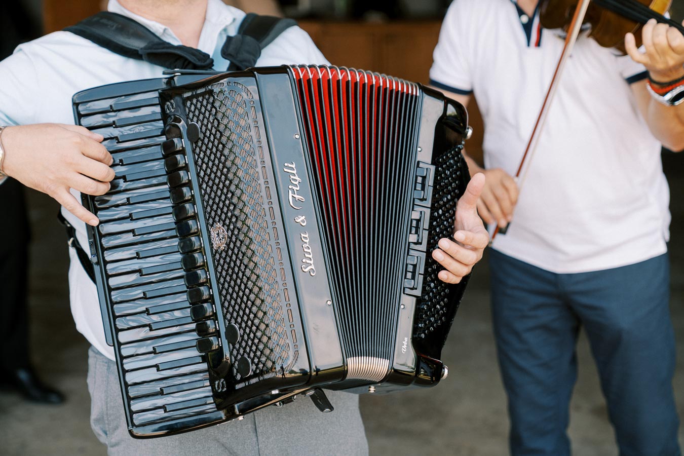 Two musicians performing, one playing an accordion and the other a violin, showcasing a lively musical atmosphere.