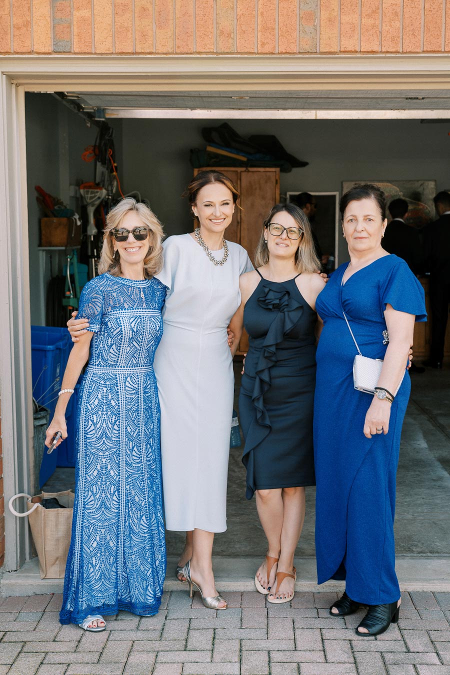 Four women posing in stylish dresses in an open garage, showcasing diverse fashion choices for a summer event.