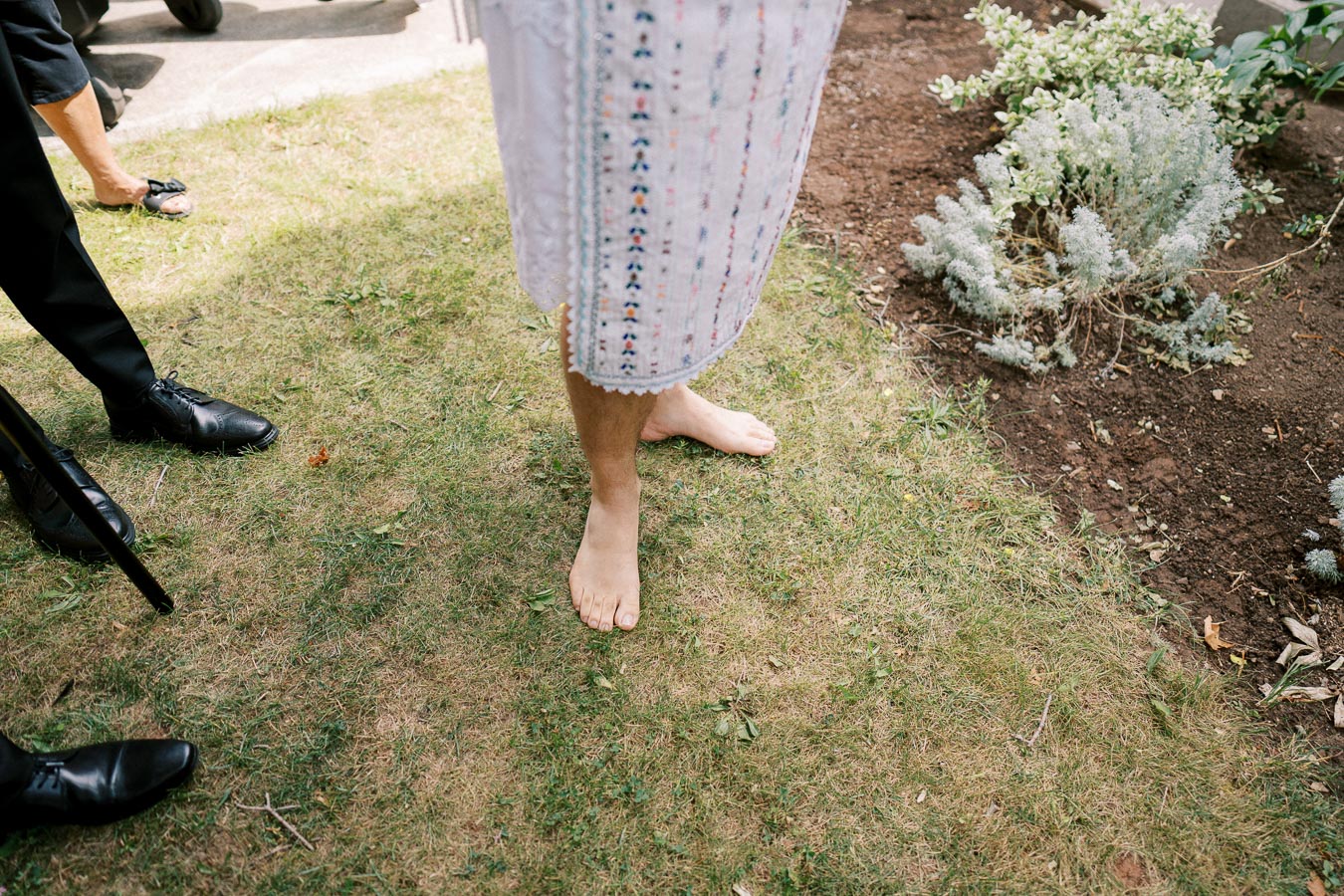 Barefoot person in traditional patterned garment standing on grass at an outdoor event.