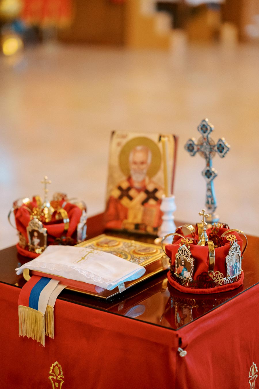 Decorative religious display featuring crowns, a cross, and an icon on a red cloth, representing a traditional Orthodox ceremony.