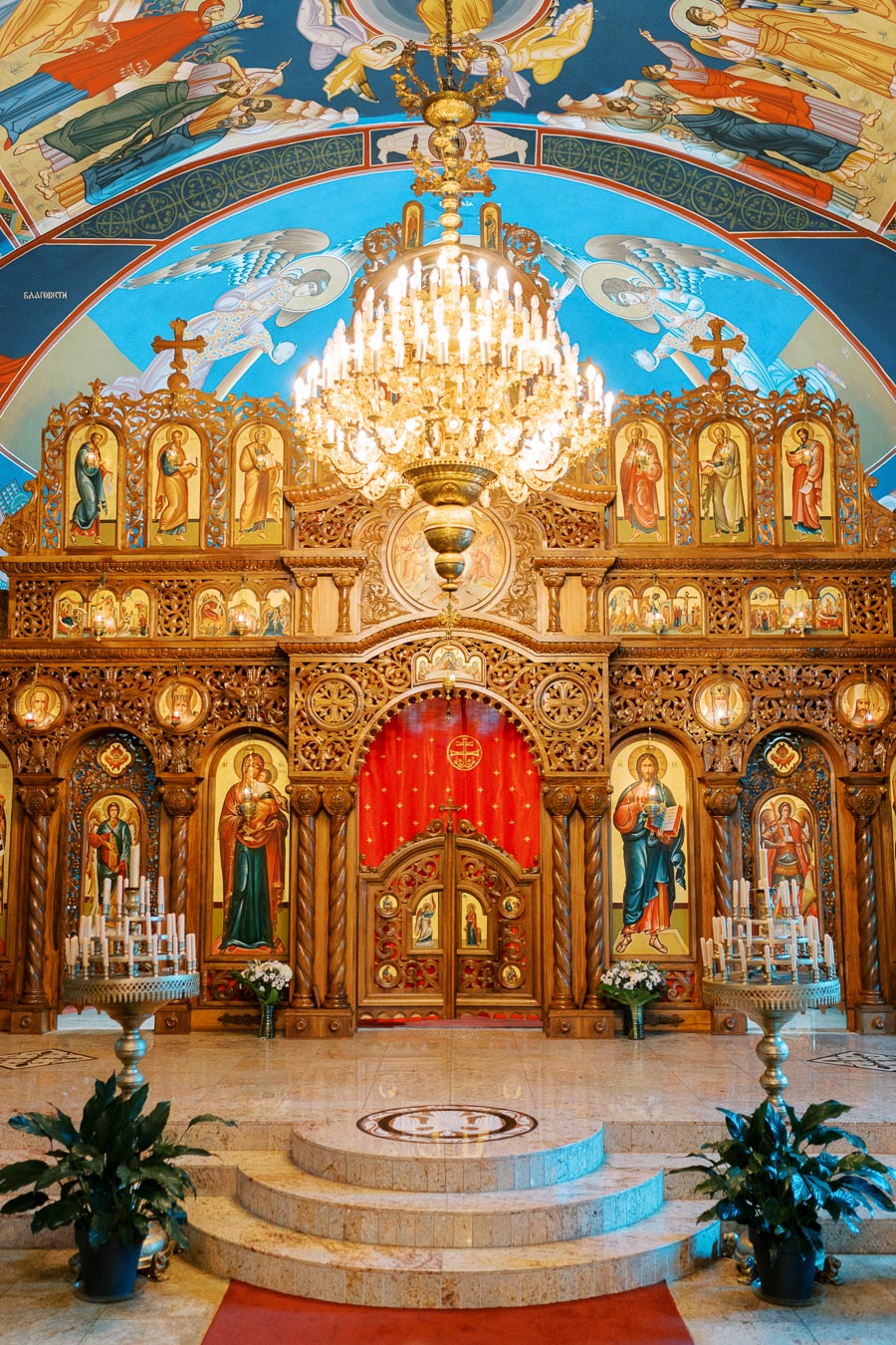 Stunning ornate interior of an Eastern Orthodox Church featuring intricately carved iconostasis, vibrant religious icons, and a grand chandelier, creating a captivating and spiritual atmosphere.