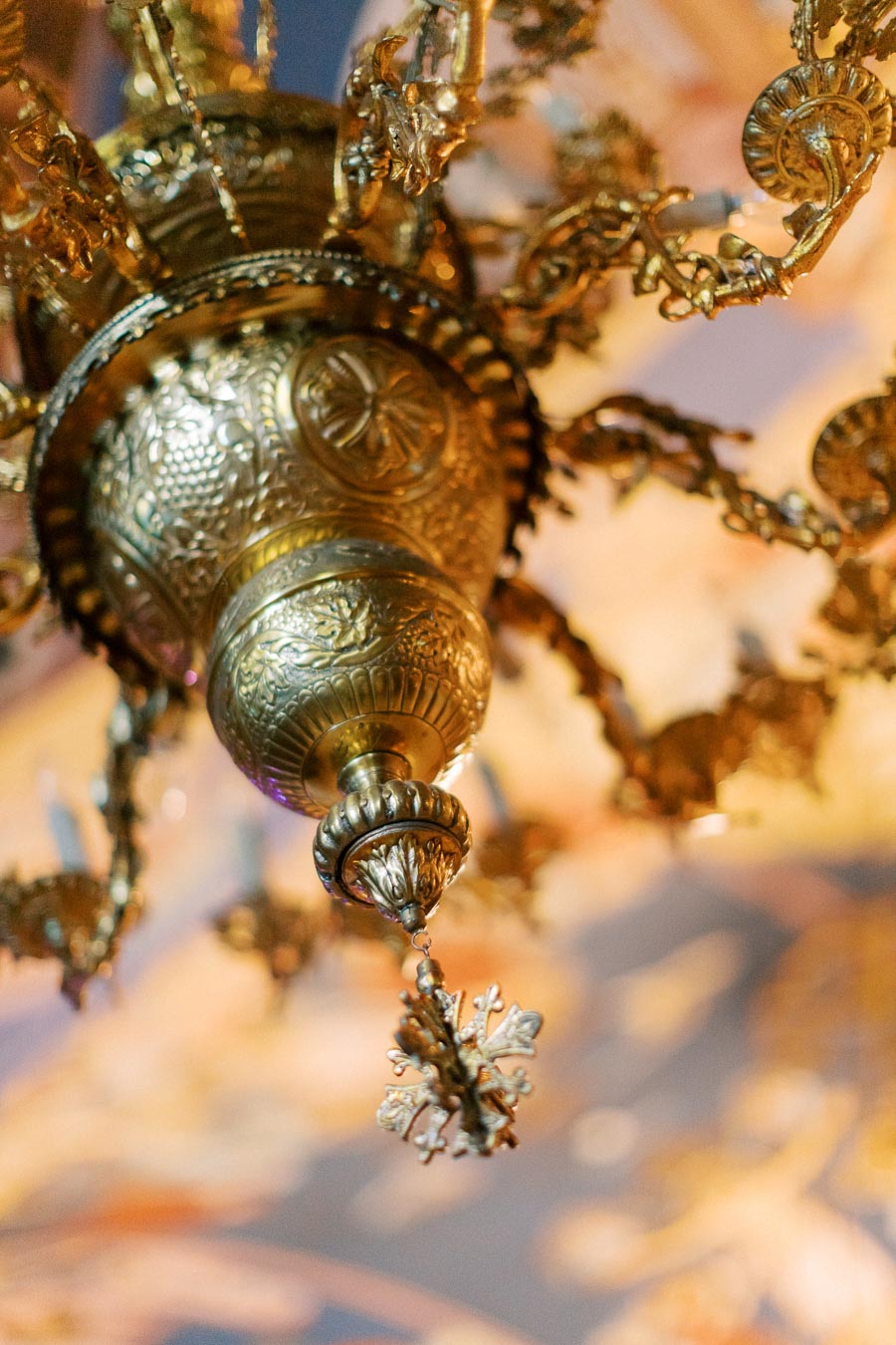 Elegant close-up of an ornate antique brass chandelier with intricate designs and decorative elements, showcasing luxury interior lighting.