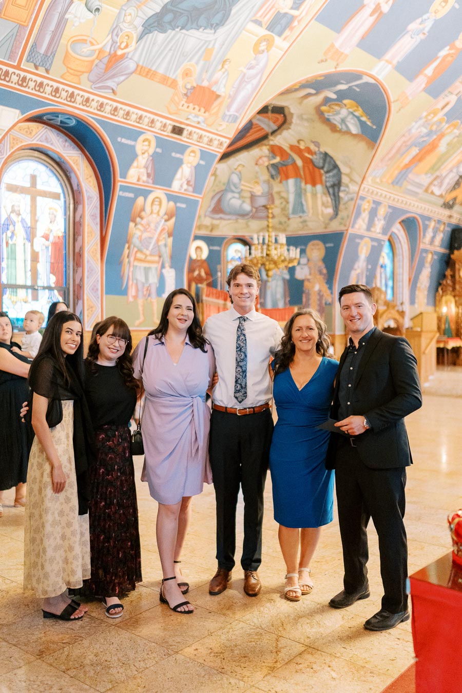 Group of six people smiling inside an ornate church with colorful murals on the walls and ceiling, showcasing a blend of traditional religious art and architecture.