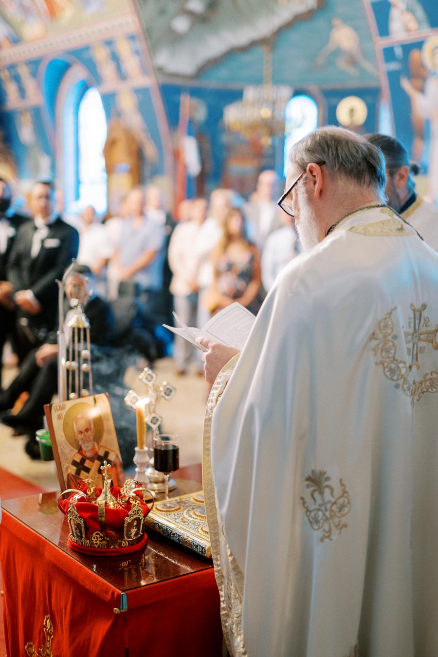 Priest conducting a religious ceremony in an ornately decorated church, with a focus on religious icons and items on the altar.