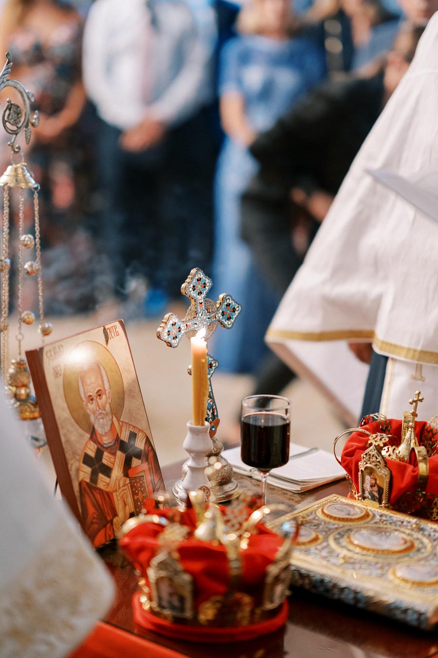 Orthodox wedding ceremony altar with religious icons, a lit candle, a cross, and ceremonial crowns, reflecting traditional Christian rituals and symbolism.