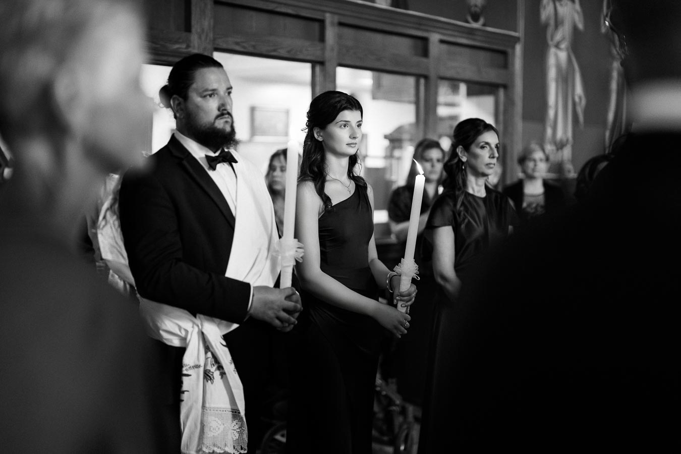 A black and white image of people dressed formally, holding large candles, standing in a ceremonial setting.