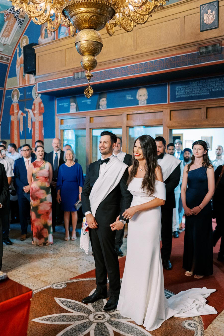 A bride and groom standing together in a church during a wedding ceremony, surrounded by guests.
