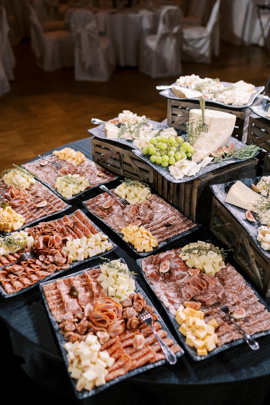 Luxurious charcuterie spread with assorted cured meats, cheeses, and fresh grapes, elegantly arranged on black platters for a gourmet event setting.