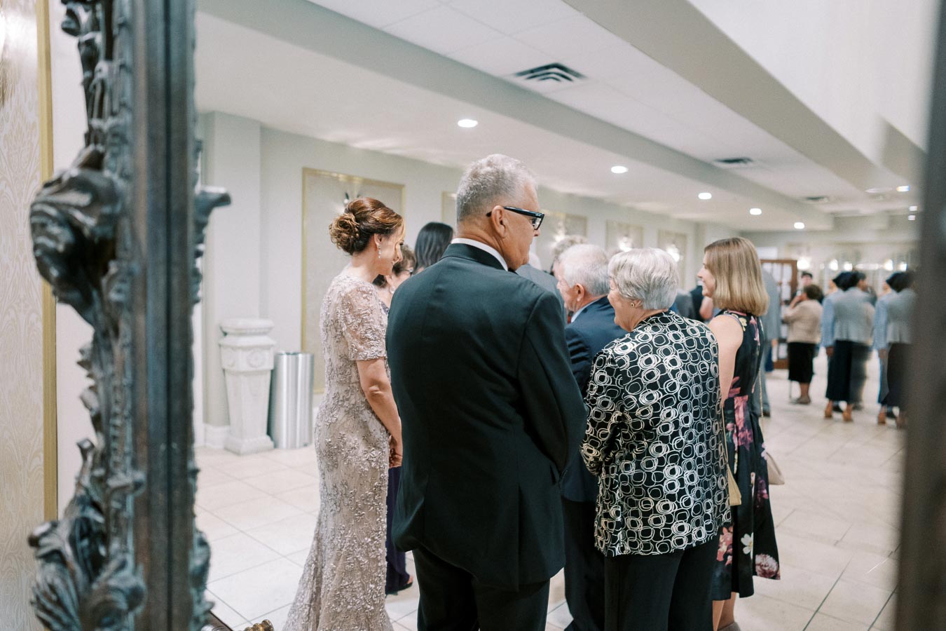 Elegant gathering of formally dressed guests at a sophisticated indoor event venue.