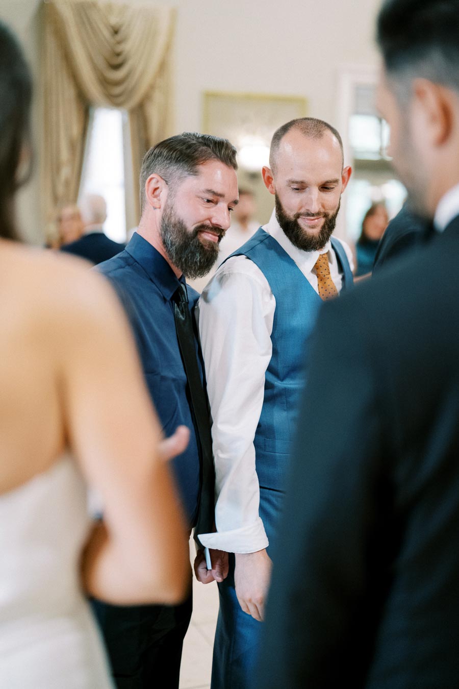 Two men in formal attire share a moment at a social gathering.