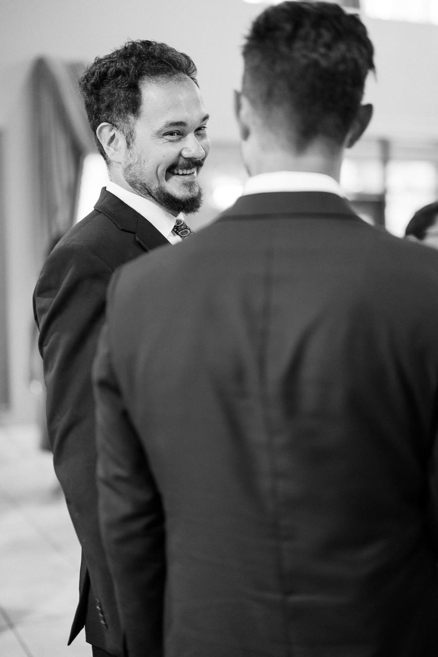 Black and white photo of two men in suits engaged in conversation, with one smiling warmly.
