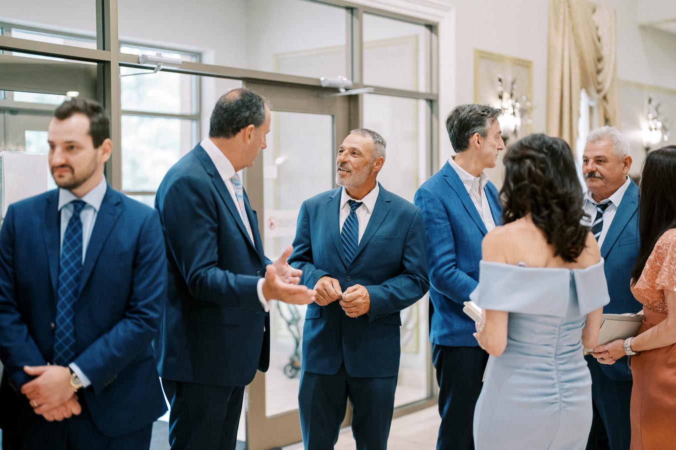 A group of formally dressed men and women engaged in conversation at a professional networking event indoors.