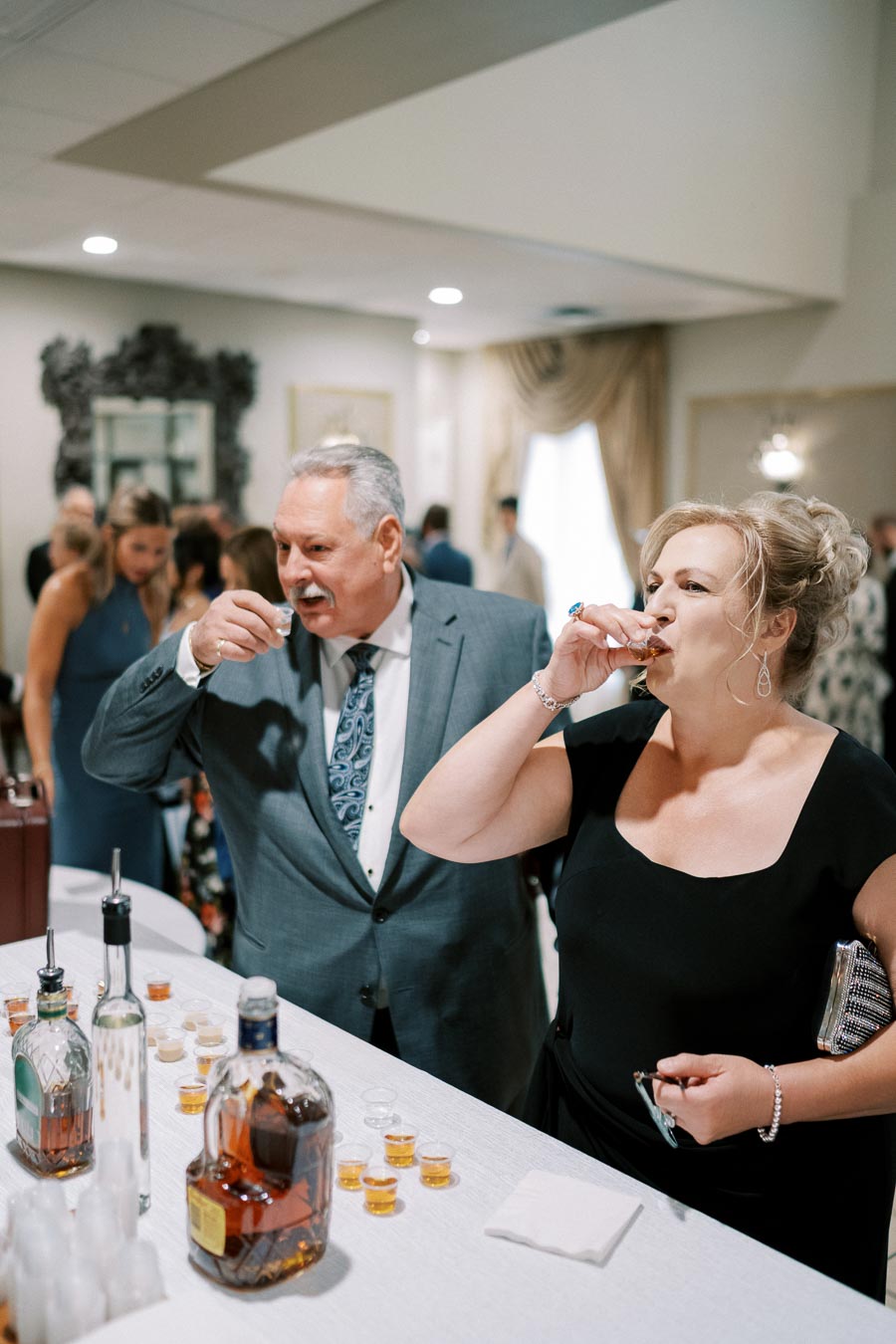 Guests enjoying whiskey tastings at an elegant event, with bottles and shot glasses neatly arranged on a table.