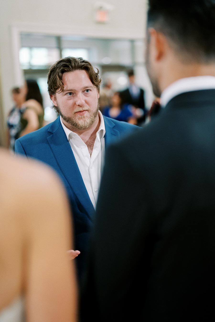Man in blue suit engaged in conversation at formal event