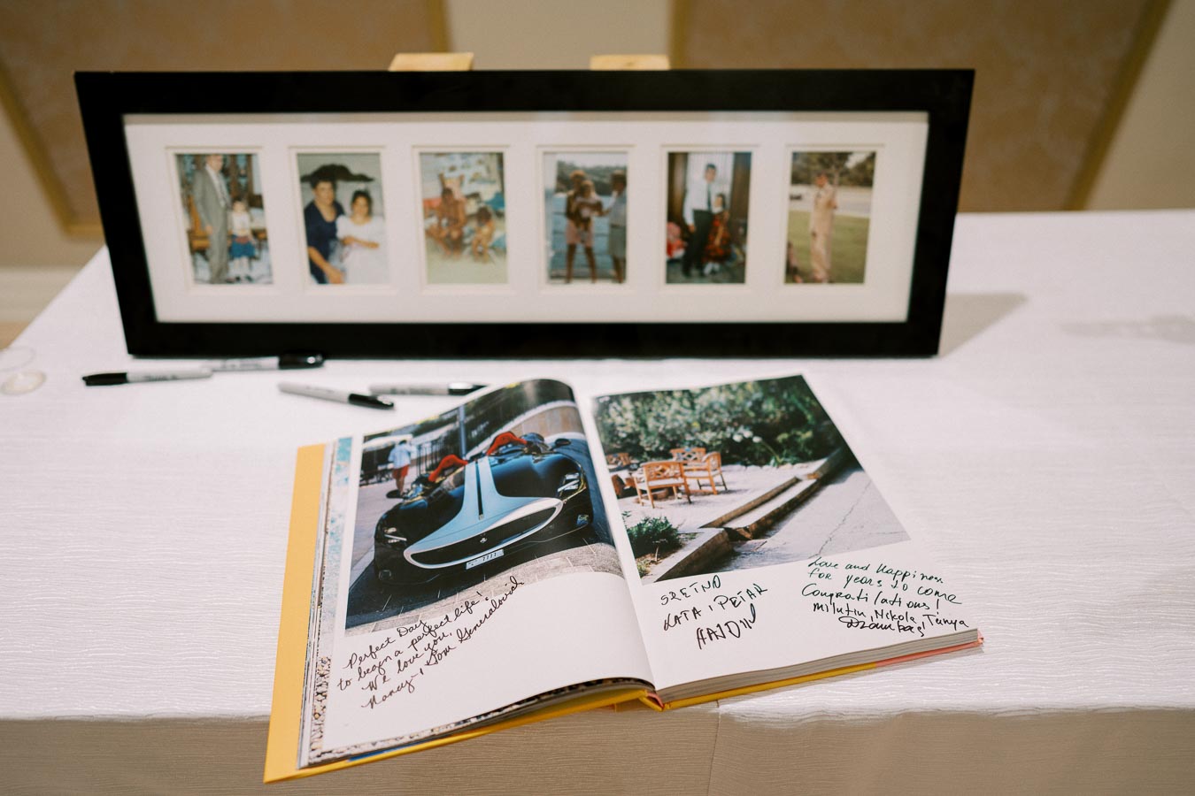 Framed family photo collage and an open guestbook with handwritten messages on a table.