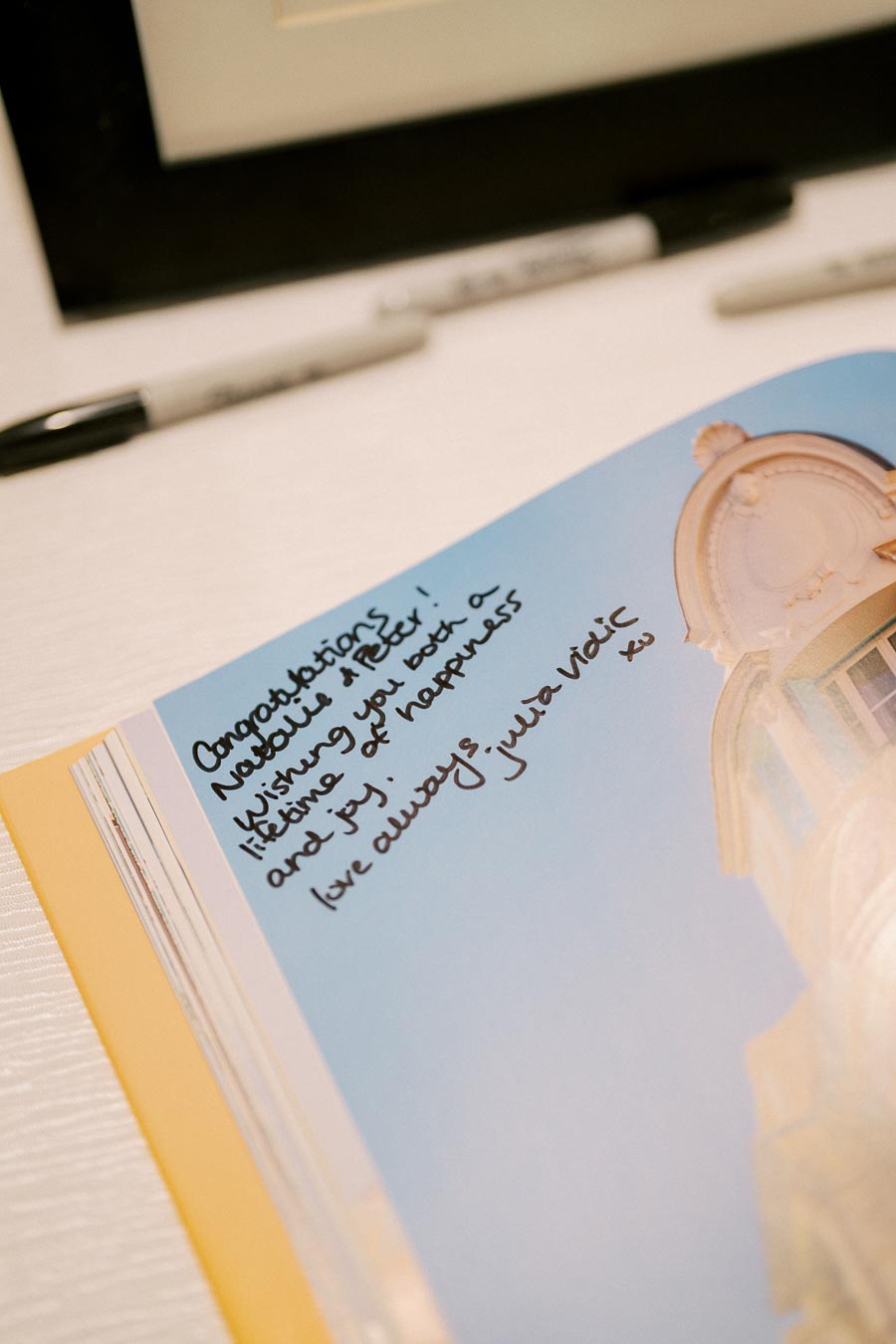 Close-up of a handwritten message on a card with a congratulatory note, alongside a pen on a table.