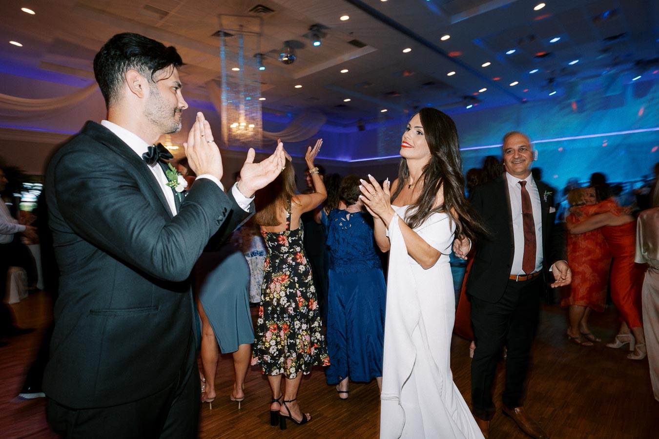 Guests joyfully dancing at a wedding reception in a beautifully decorated venue, wearing elegant formal attire.
